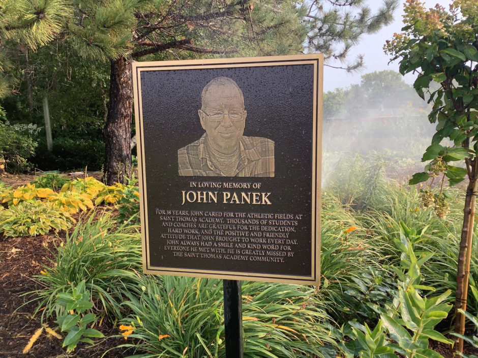 Bronze memorial plaque for John Panek at Saint Thomas Academy, honoring his 38 years of dedication to the athletic fields.