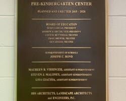 Bronze plaque #10 cast bronze plaque, flat band beveled border, brown background, leatherette texture, concealed stud mounted on cinder block wall.